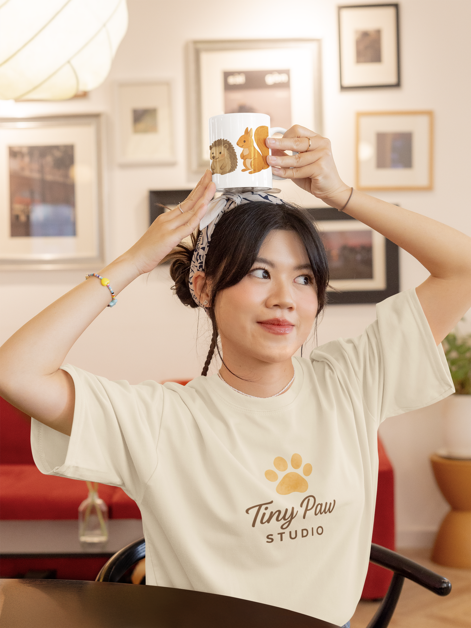 Woman wearing a Tiny Paw Studio t-shirt playfully placing a mug on her head – quirky mug design for animal lovers